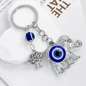 Detailed close-up of a silver elephant keychain with a blue evil eye and tree charm.