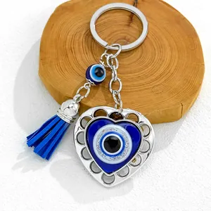 Detail of heart-shaped evil eye keychain with blue tassel on a wood block.