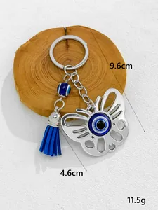 Close-up detail of a silver evil eye butterfly keychain featuring a vibrant blue tassel
