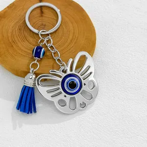 Detailed view of silver butterfly keychain featuring blue evil eye bead and tassel