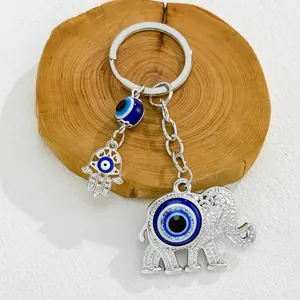 Detailed view of silver elephant keychain with blue evil eye and hamsa hand charms