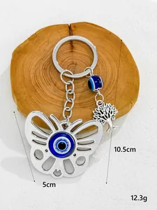Detail view of silver butterfly keychain with blue evil eye bead and tree charm