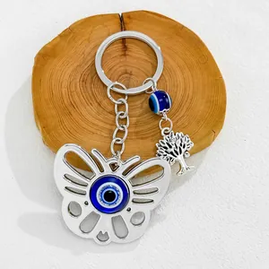 Detail view of silver butterfly keychain featuring blue evil eye and tree of life charms