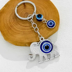 Detailed view of a silver elephant keychain with blue evil eye beads on a wood slice