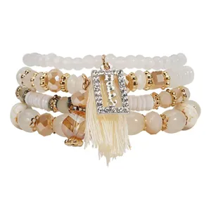 Vista dettagliata del set di 4 bracciali di perline con ciondolo Happy in strass e nappa