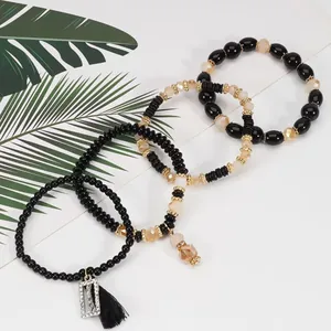 Elegante set di quattro braccialetti di perle nere e color champagne con ciondolo Happy