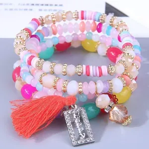 Primo piano di un set di bracciali con perline colorate, nappa e ciondolo Happy