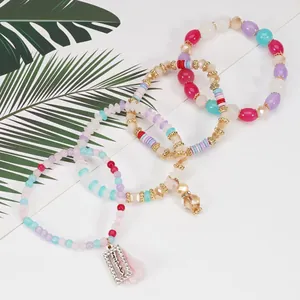 Dettaglio di un set di quattro braccialetti di perline con ciondolo Happy e nappa rosa.