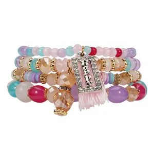Dettaglio del set di braccialetti multistrato con perle di cristallo e ciondolo Happy