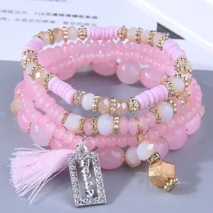 Dettaglio ravvicinato del set di braccialetti di perline rosa con ciondolo HAPPY e nappa