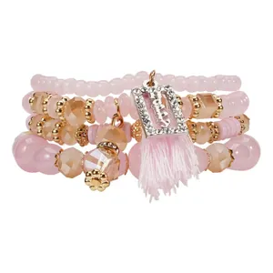 Dettaglio dei braccialetti rosa a strati con perline, nappa e ciondolo happy