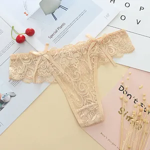 Close-up of beige lace thong with bow details and delicate floral jacquard patterns.