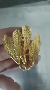 Detaillierte Nahaufnahme eines goldenen Metall-Serviettenrings in Blattform mit Struktur.