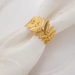 Vue détaillée d'un rond de serviette en feuille dorée montrant des textures sur tissu blanc