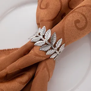 Gros plan détaillé d'un rond de serviette argenté avec motif feuille ciselé.
