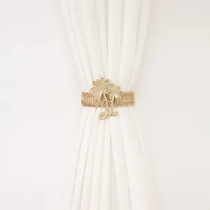 Close-up view of golden palm tree napkin ring with elegant metallic texture and white fabric