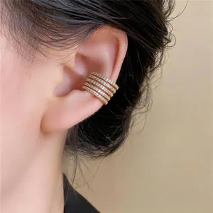 Primo piano di un elegante ear cuff multistrato in oro con zirconi bianchi lucidi.