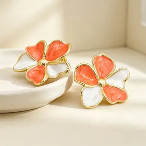 Nahaufnahme von Vintage-Emaille-Blumenohrringen mit orange-weiß marmorierten Blüten.