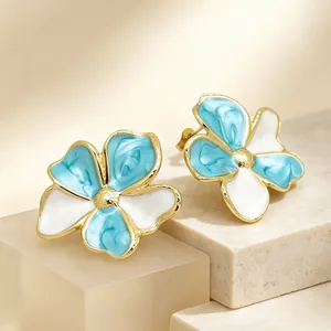 Detailaufnahme von retro blau und weiß emaillierten Blumenohrringen in Goldoptik