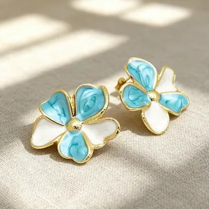 Detailaufnahme der blau-weißen Emaille-Blumenohrringe mit einer goldfarbenen Fassung