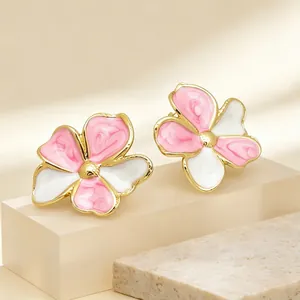 Exquisite Nahaufnahme von rosa-weißen Emaille-Blumenohrsteckern mit edlem Goldrand