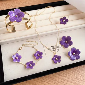 Detailed view of elegant purple enamel flower jewelry set in a white display box