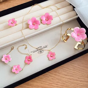 Detailed view of a pink enamel flower jewelry set presented in a cream display tray