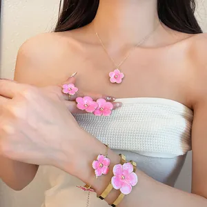 Detail of pink enamel flower jewelry set worn by model including necklace and bracelets