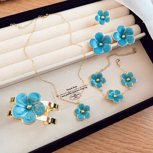 Elegant blue enamel flower jewelry set including necklace, bracelet, and earrings in a box.