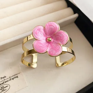 Close-up of a pink enamel flower cuff bracelet in gold finish for island vacation style
