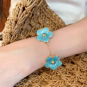 Close-up of blue enamel flower charm bracelet worn on a woman's wrist
