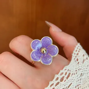 Macro detail of a vintage style purple enamel flower ring with golden metallic accents