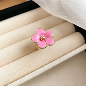 Close-up detail of a pink enamel flower ring with gold finish in a jewelry display case