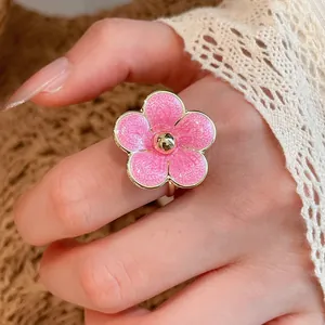 Detailed shot of a delicate pink enamel flower ring worn on a hand, resort style.