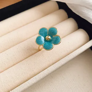 Macro detail view showing a turquoise blue enamel flower ring displayed in a cream jewelry box