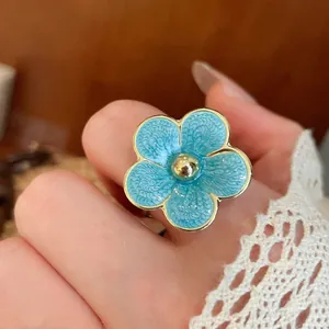 Detailed close-up showing a delicate light blue enamel flower ring with elegant golden edges
