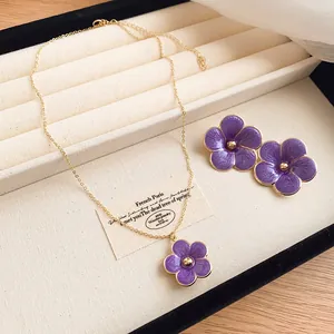 Detailed view of the purple enamel flower necklace and stud earrings in a luxury jewelry box