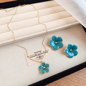 Detail view of blue enameled flower pendant necklace and stud earrings set