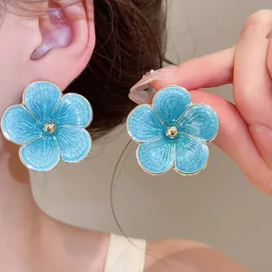 Detailed macro view of elegant blue enamel flower earrings with gold-toned trim
