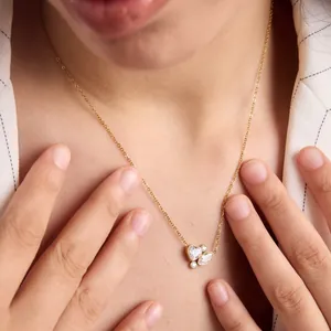 Detalle de un collar bañado en oro de 18k con colgante de corazón de circón en modelo.