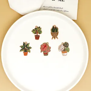 Ensemble détaillé de cinq breloques de plantes en émail pour bijoux DIY sur plateau blanc