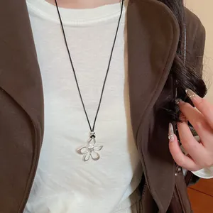 Dettaglio di un ciondolo geometrico irregolare in argento su un cordoncino nero fine