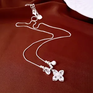 Elegant silver four-leaf clover pendant necklace with zircon and pearl on brown silk.