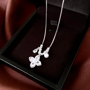 Close-up of silver clover pendant necklace with zircons and pearl in a jewelry box