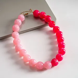 Primer plano de cuentas de acrílico marbreado en un collar degradado rosa dopamina