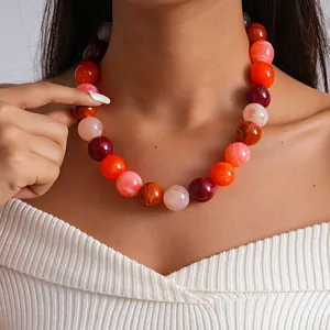 Primer plano de un collar de perlas de acrílico veteado con colores vibrantes en modelo