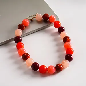 Vista detallada de primer plano de collar de acrílico con cuentas jaspeadas rojas y rosas.