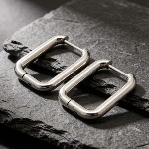 Close-up detail of U-shaped stainless steel geometric earrings on stone background
