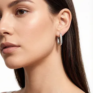 Detail shot of a silver U-shaped hoop earring with sparkling stones on a female model.