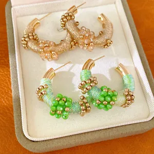 Detalle de pendientes de aro en C estilo vintage francés con hilo tejido y cuentas